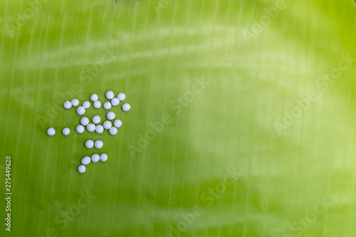 Homeopathy - Homeopathic globule scattered on banana leaf background