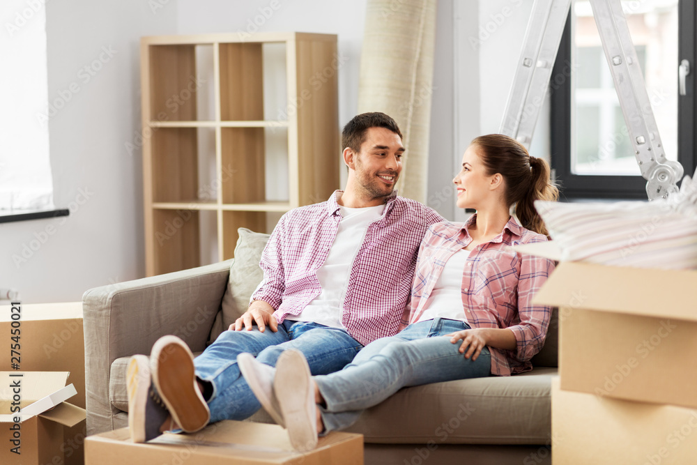 moving, people, repair and real estate concept - happy couple with cardboard boxes sitting on sofa at new home moving, people, repair and real estate concept - happy couple with cardboard boxes sitting on sofa at new home