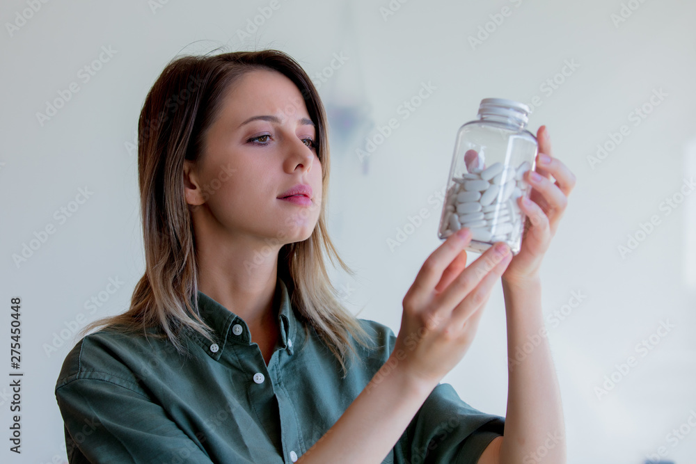 woman holding a transparent jar with white pills woman holding a transparent jar with white pills