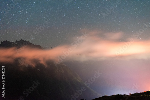 night sky with stars over the mountains with clouds in the mountain resort Dombay