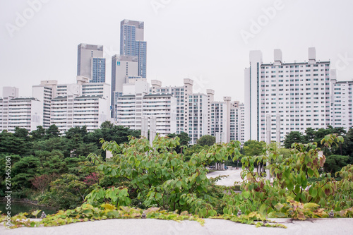 The view of the oriental garden and lake in Seoul, South Korea. There are apartment complex and buildings in the distance. © Koshiro