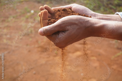 Hand man holding red soil dust on the blur background  © yudhistirama