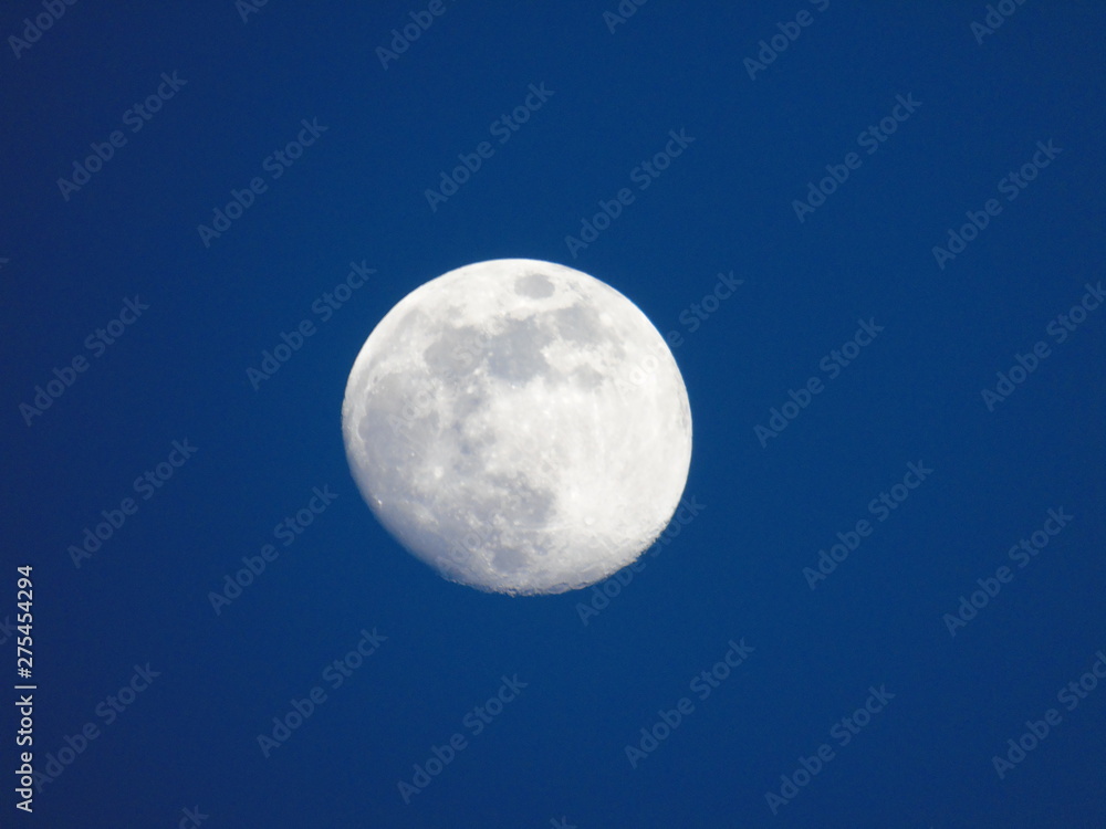 Genova, Italy - 06/15/2019: An amazing photography of the full moon over the city of Genova by night with a great clear and blue sky in the background and some stars.