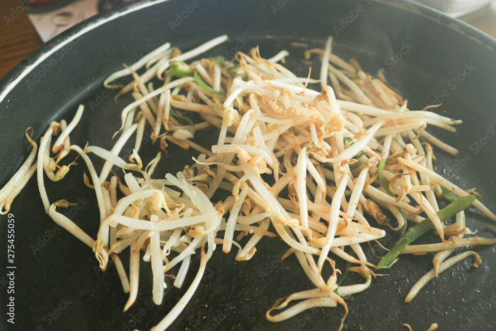 fried bean sprouts with smoke on black pan close up shot