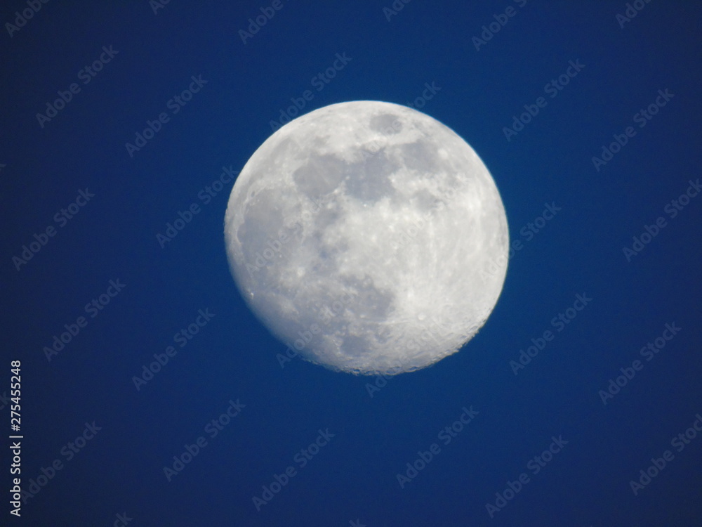 Genova, Italy - 06/15/2019: An amazing photography of the full moon over the city of Genova by night with a great clear and blue sky in the background and some stars.