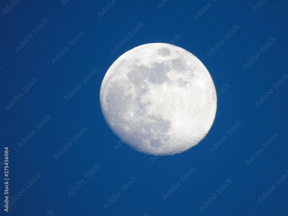 Genova, Italy - 06/15/2019: An amazing photography of the full moon over the city of Genova by night with a great clear and blue sky in the background and some stars.