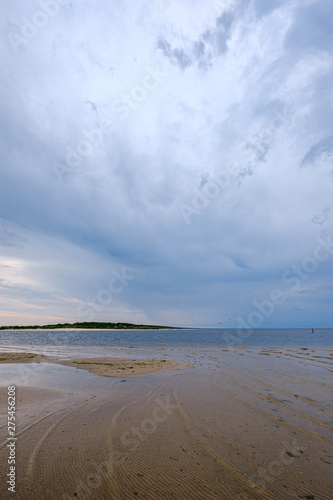 dramatic colorful clouds over sandy beach at the sea with blue sky