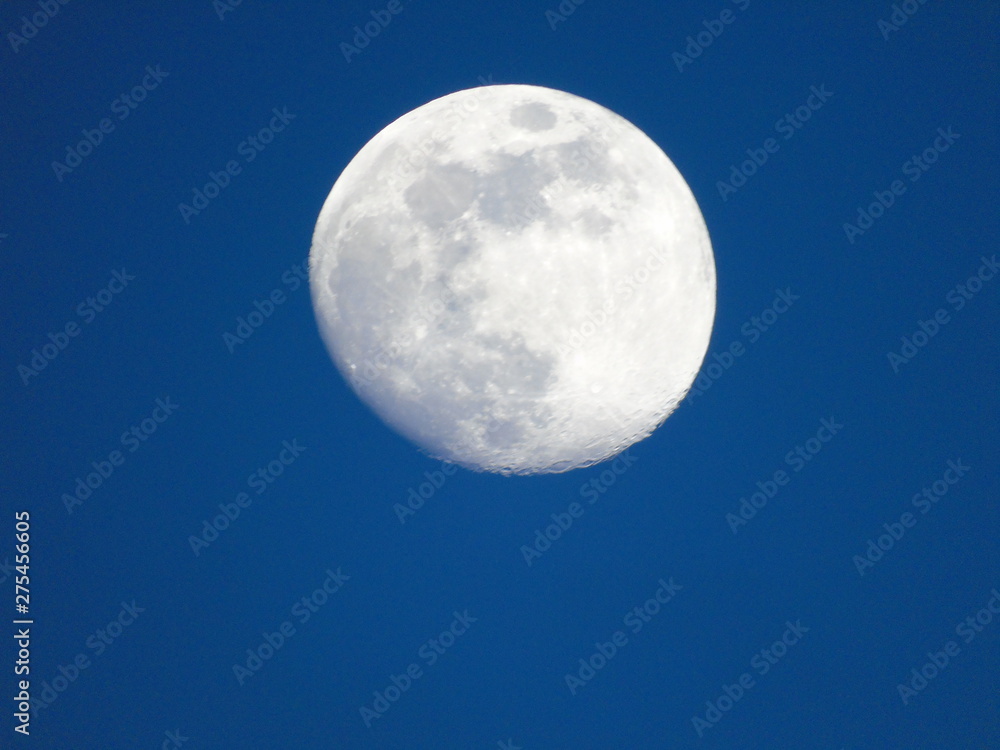 Genova, Italy - 06/15/2019: An amazing photography of the full moon over the city of Genova by night with a great clear and blue sky in the background and some stars.