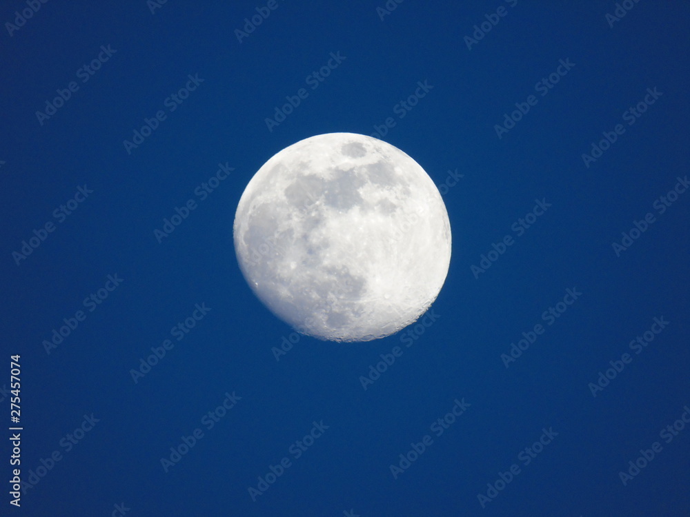 Genova, Italy - 06/15/2019: An amazing photography of the full moon over the city of Genova by night with a great clear and blue sky in the background and some stars.