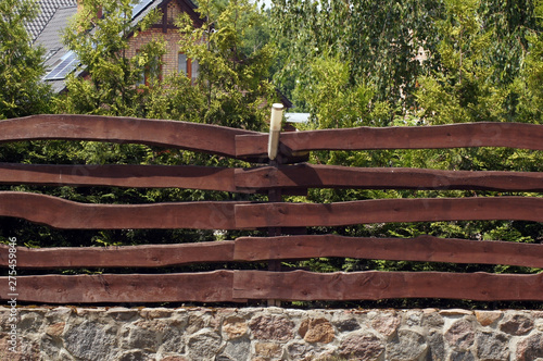 Rustikaler Gartenzaun aus dunklem Holz