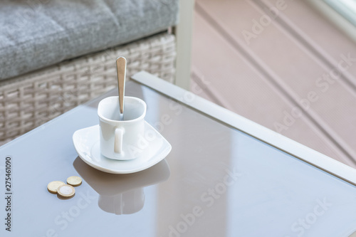 Fotografija small change in a euro and empty cup of coffee on a glass table of outdoor cafe