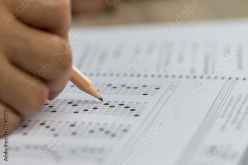 Education school test concept : Hands student holding pencil for testing exams writing answer sheet or exercise for taking fill in admission exam multiple carbon paper computer at university classroom