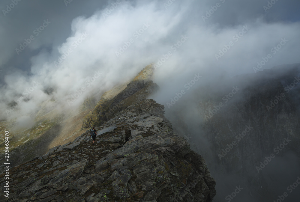 A hiker on a mountain ridge, hiking the Via Alta Verzasca in Ticino, Switzerland.