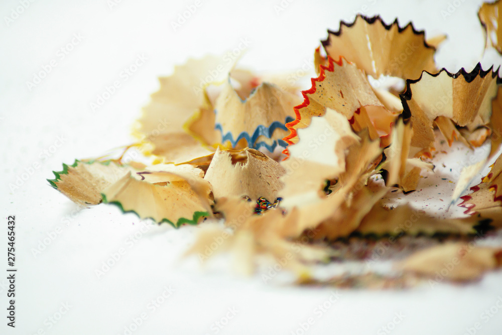 Wooden pencil shavings on white paper background and colorful crumbs of graphite from sharpener. Wooden pencil shavings on white paper background and colorful crumbs of graphite from sharpener.