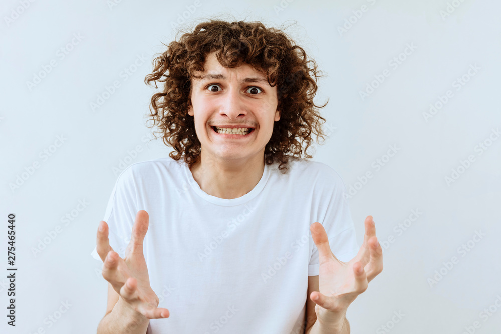 Furious, Frustrated and stress emotion. Portrait of Curly teen guy against white background Furious, Frustrated and stress emotion. Portrait of Curly teen guy against white background