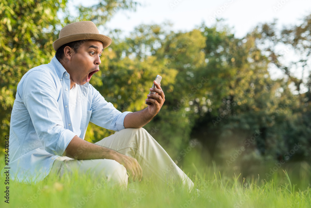 Fototapeta premium Asian man using smartphone in park
