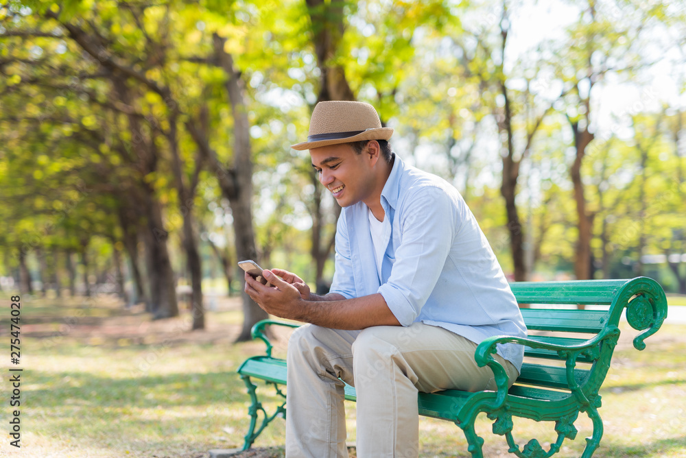 Fototapeta premium Asian man using smartphone in park