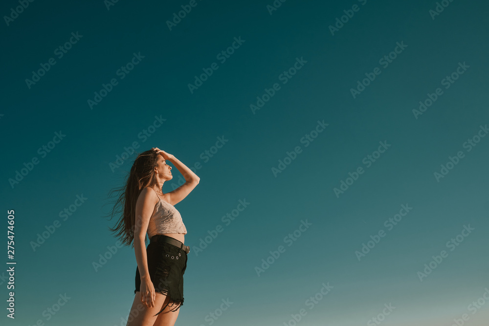 Fototapeta premium a young woman in a summer day with a blue sky - negative space