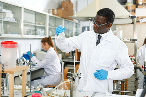 Man proffesional lab scientist in glasses working with reagents and test tubes