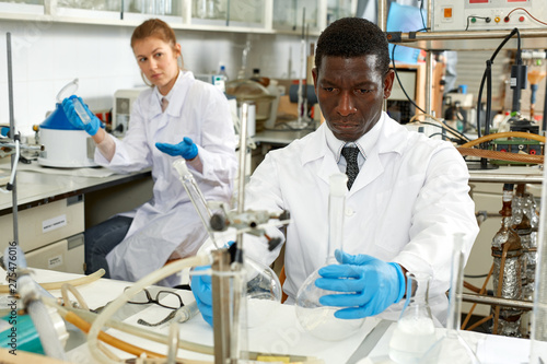 Male lab technicians with different glass tubes  girl on background