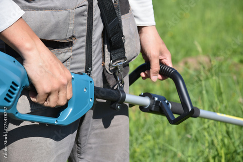 trimmer mows grown grass on the lawn forming a circle. Trimmer close up mow the grass with a lawnmower. Gardening with a brush cutter Close-up. Lawn care with brush cutters.