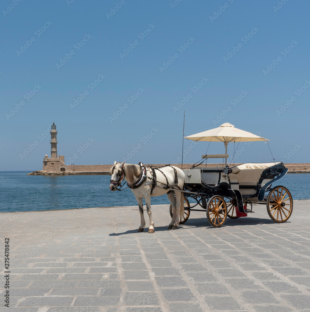 Chania, Crete, Greece, June 2019. Horse drawn carriage waiting on the Old Venetion Harbour in Chania to take passengers on a ride.