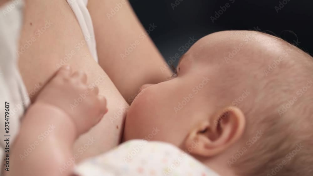 Close up of newborn baby touching mothers breast while sucking milk. Breastfeeding concept. Close up of newborn baby touching mothers breast while sucking milk. Breastfeeding concept.