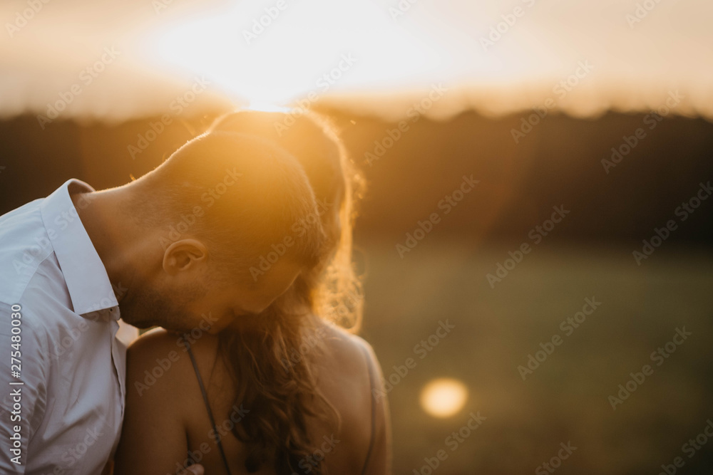 couple in love in a field at sunset in the summer smiling and happily hugging. engagement concept, weddings in nature. couple in love in a field at sunset in the summer smiling and happily hugging. engagement concept, weddings in nature.