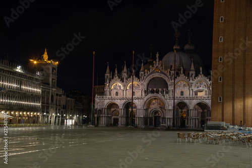 Night photography of the Basilica di San Marco and the clock tower, Venice, Italy. View of the facade with mosaics and golden domes.