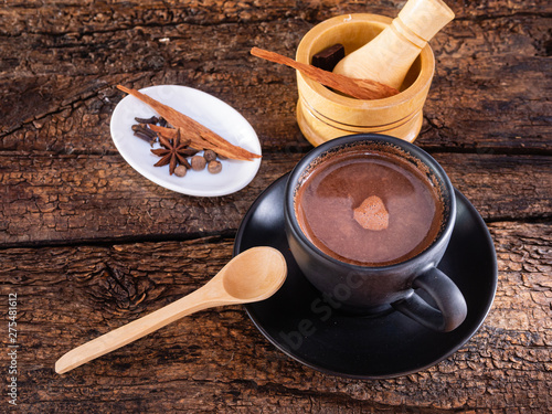 Cup of chocolate with spices and mortar on an authentic old table