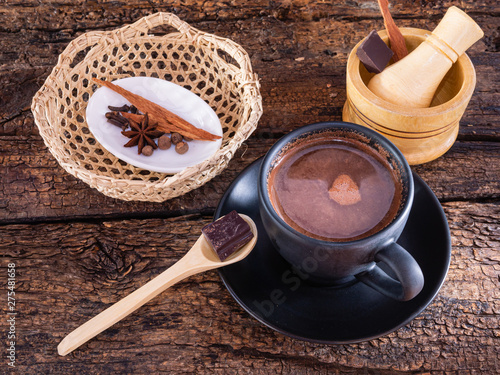 Cup of chocolate with spices and mortar on an authentic old table