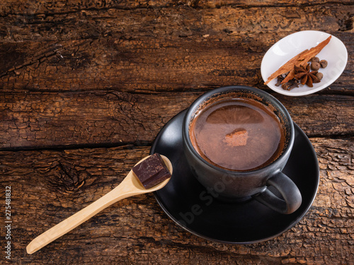 Cup of chocolate with spices and mortar on an authentic old table