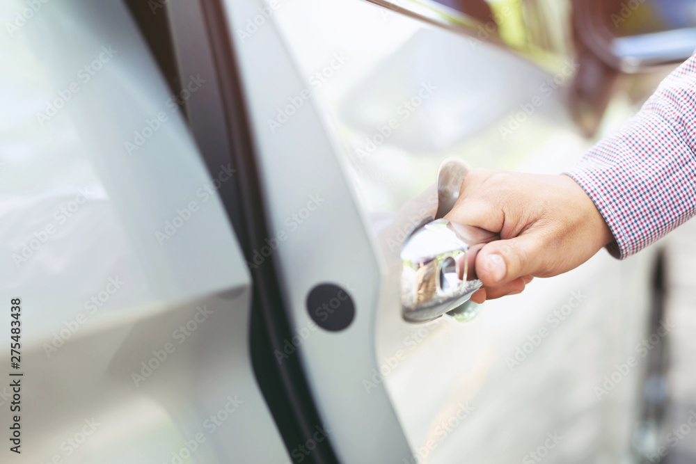 Obraz premium Close up image of a businessman hand on handle opening a car door. Pull the door to you.