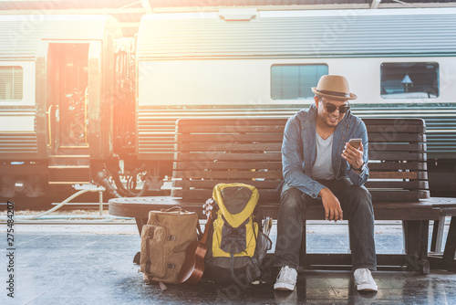 Young handsome man sitting and using smartphone at train station