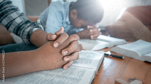 Two christian praying on wooden table with bible. photo