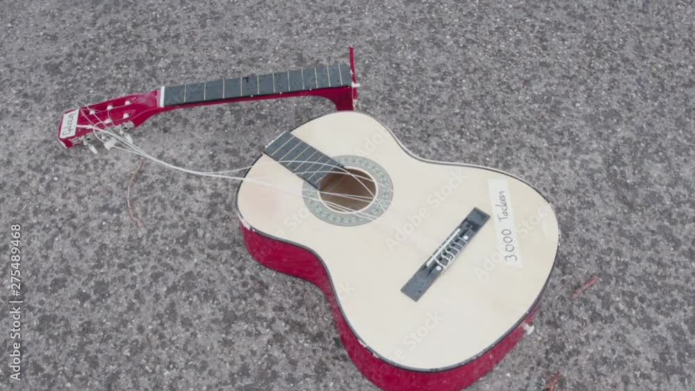 [Rotation] Acoustic guitar lies smashed on the ground. Camera rotates