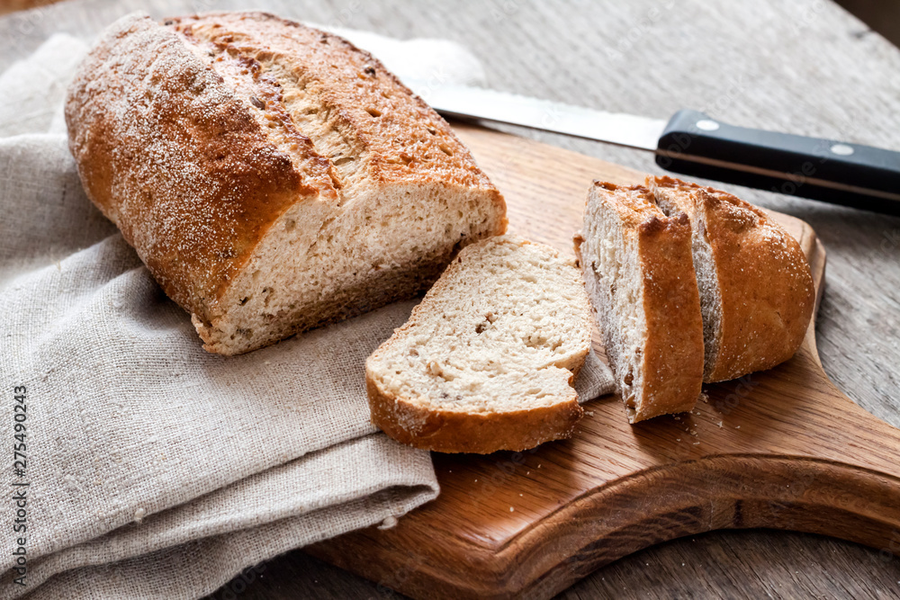 Loaf of whole wheat bread with slices on wooden board Loaf of whole wheat bread with slices on wooden board