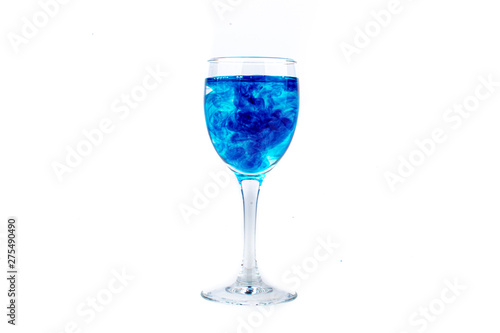 Blue food coloring diffuse in water inside wine glass with empty copyspace area for slogan or advertising text message, over isolated white background.