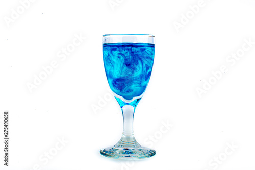 Blue food coloring diffuse in water inside wine glass with empty copyspace area for slogan or advertising text message, over isolated white background.