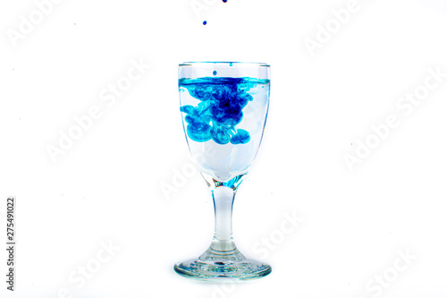 Blue food coloring diffuse in water inside wine glass with empty copyspace area for slogan or advertising text message  over isolated white background.