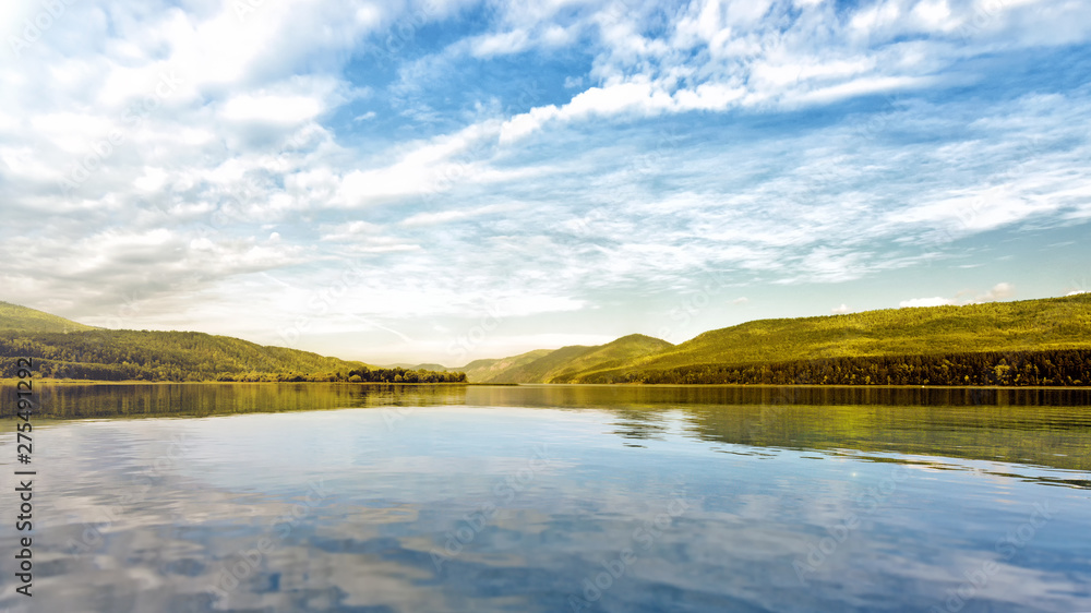 Fototapeta premium river water on forest mountains background lake and mountain landscape panorama ground view of beautiful autumn nature with white clouds blue sky and scenery reflection in water travel outdoor concept