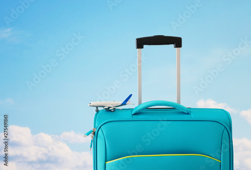 holidays. travel concept. blue suitcase and airplane toy infront of sky background