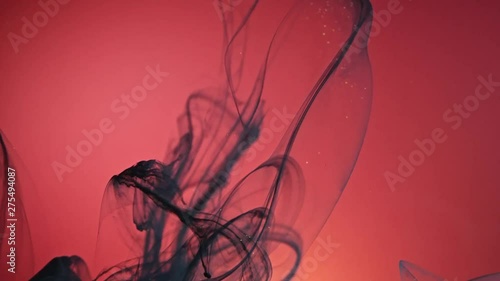 Black nacreous paint in water against red background.