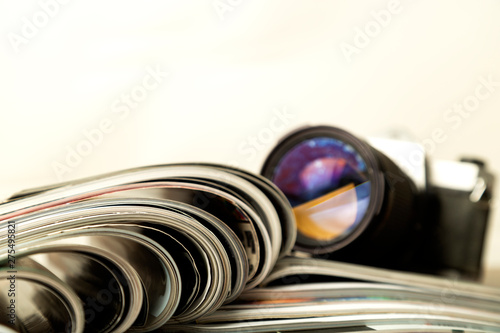 Stack of magazines with digital camera in back and copy space.