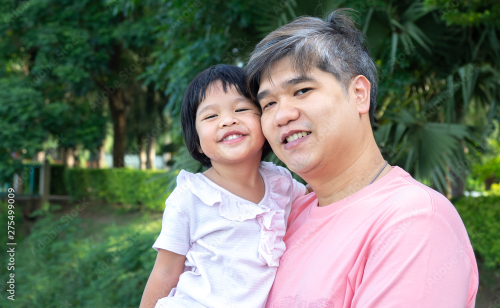 An Asian father is carrying a lovely daughter to her chest. Both the father and daughter smiled happily. Asia family and love concept An Asian father is carrying a lovely daughter to her chest. Both the father and daughter smiled happily. Asia family and love concept