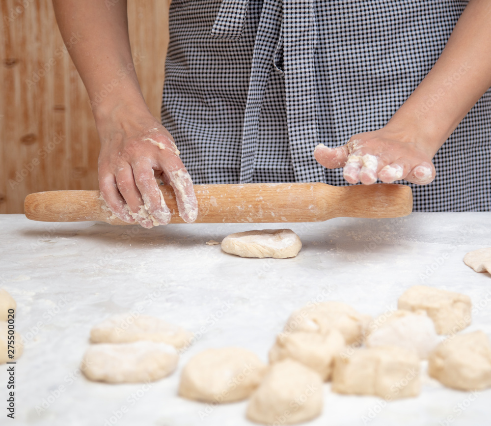 Obraz premium Girl rolls the dough in the kitchen