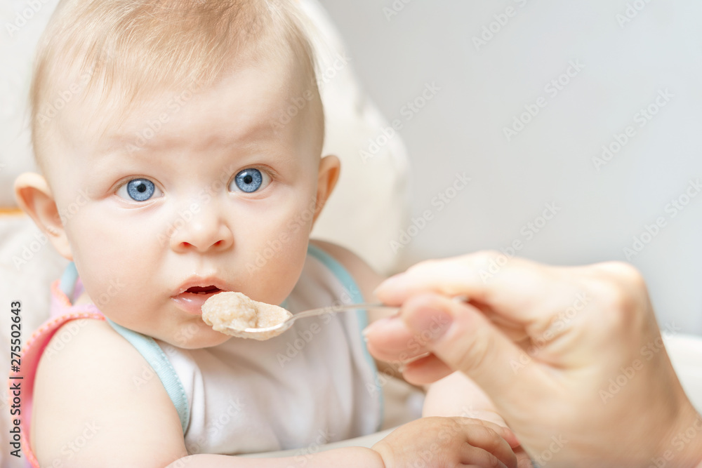 mother feeding her baby boy with a spoon mother feeding her baby boy with a spoon