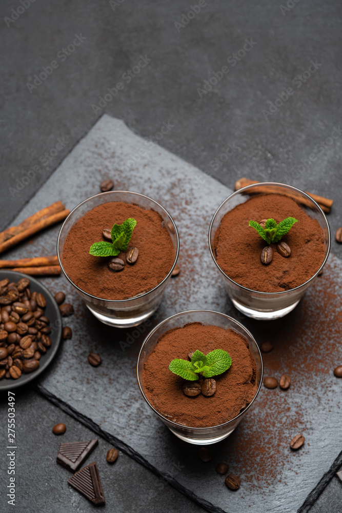 Classic tiramisu dessert in a glass on stone serving board on dark concrete background Classic tiramisu dessert in a glass on stone serving board on dark concrete background