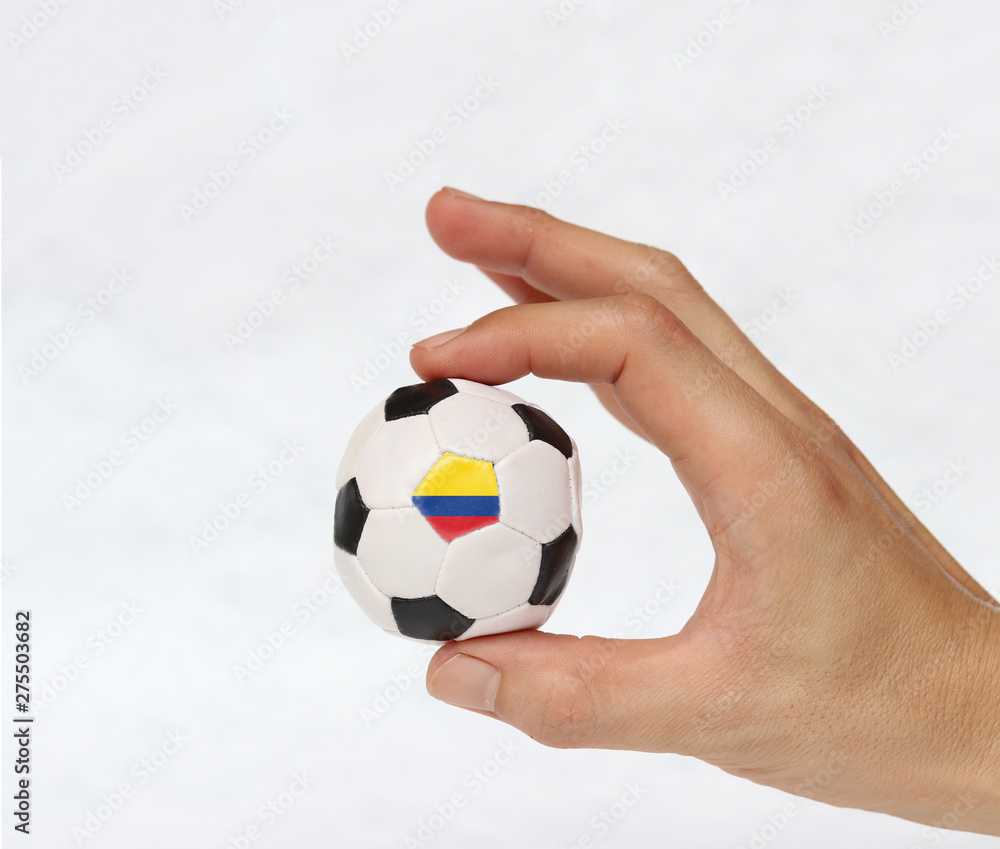 Mini ball of football in hand and one black point of football is Colombia flag, hold it with two finger on white background. Concept of sport or the game in handle or minor matter. Mini ball of football in hand and one black point of football is Colombia flag, hold it with two finger on white background. Concept of sport or the game in handle or minor matter.