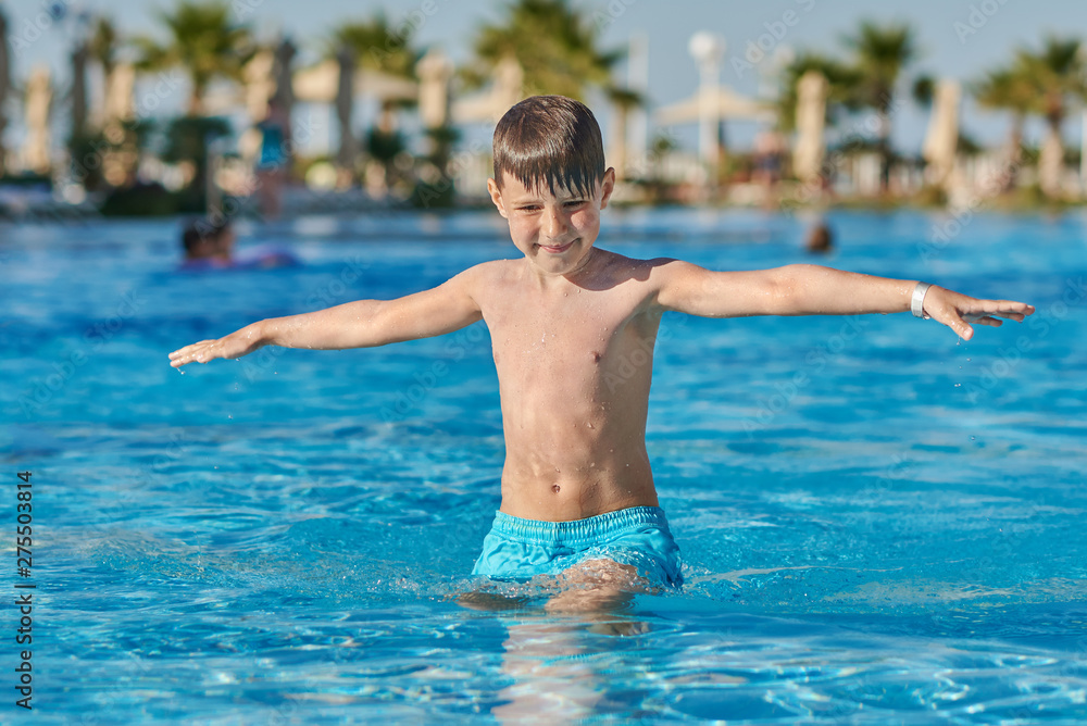 Smiling Caucasian boy having fun in pool at resort. His hands are open wide. Smiling Caucasian boy having fun in pool at resort. His hands are open wide.